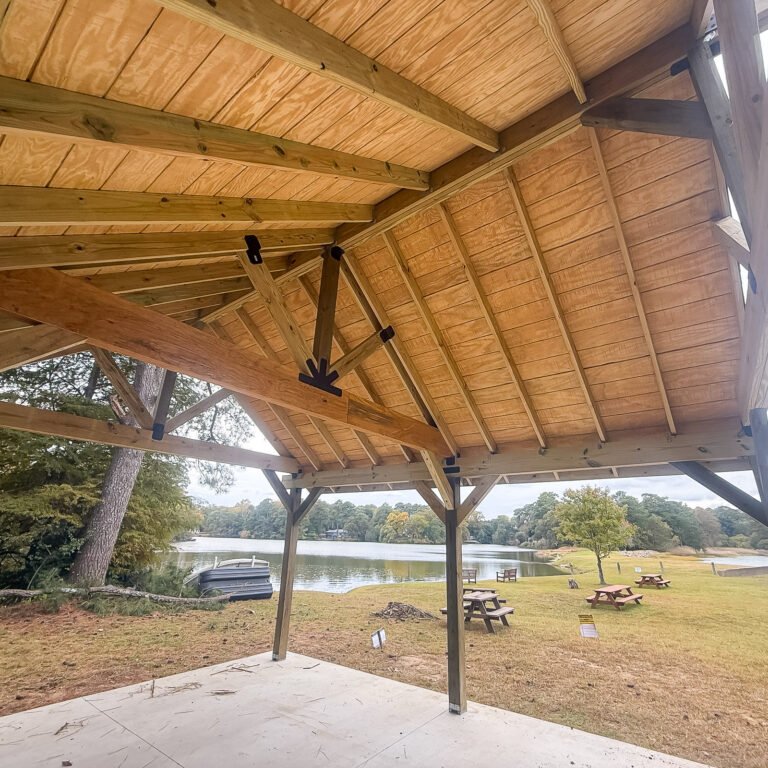 Timber-framed covered patio with exposed roof beams and a ceiling fan.