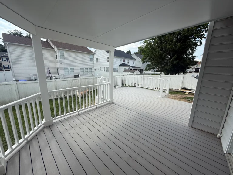Completed composite deck with white railings and a patio cover
