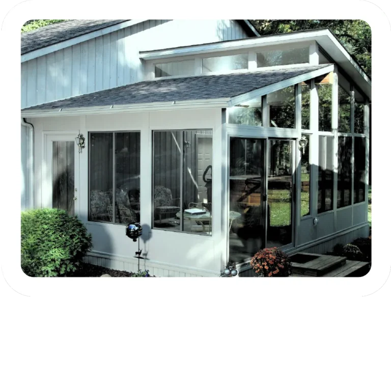 White-framed glass sunroom beside a garden terrace.